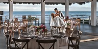 A bride and groom share their first dance at a destination wedding at Ocean Maya Royale, surrounded by beautifully set tables overlooking the ocean.
