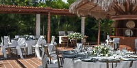 Ocean Maya Royale destination wedding setup features round tables adorned with elegant white linens and stunning floral centerpieces, creating a beautiful outdoor wedding atmosphere.