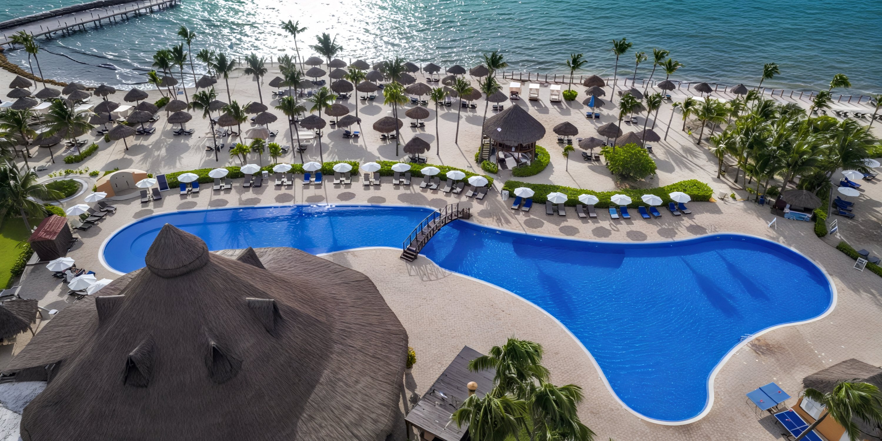 Aerial view of the Ocean Coral and Turquesa resort pool, featuring lounge chairs along a sandy beach—an idyllic setting for a destination wedding.