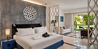 Ocean Maya Royale room: Perfect for a destination wedding stay, this inviting space offers a king bed, cozy seating area, and picturesque garden views through large windows.
