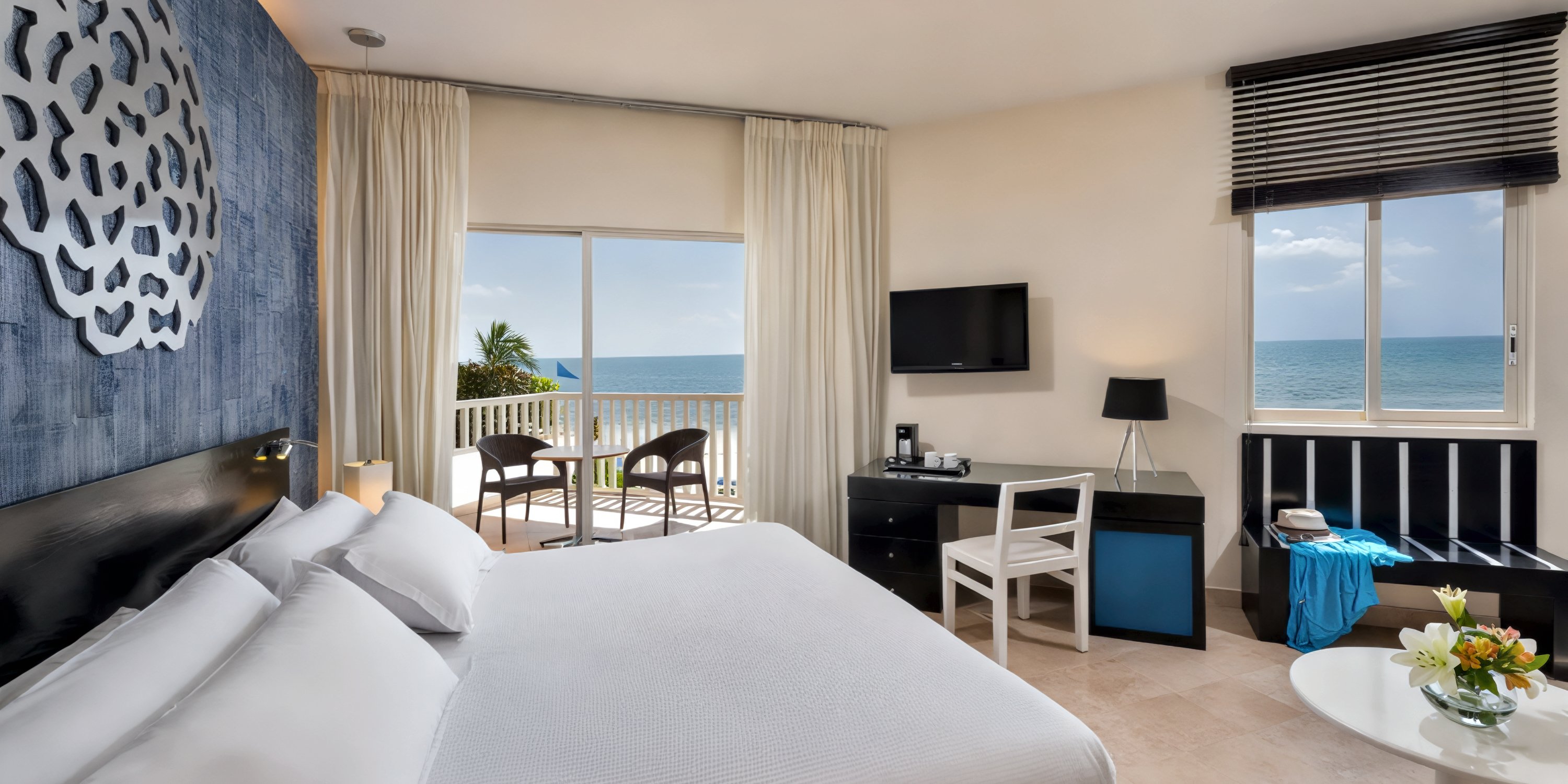 Ocean Maya Royale room: Perfect for a destination wedding, this room features a comfortable bed, desk, TV, and balcony chairs with stunning ocean views through sliding doors.