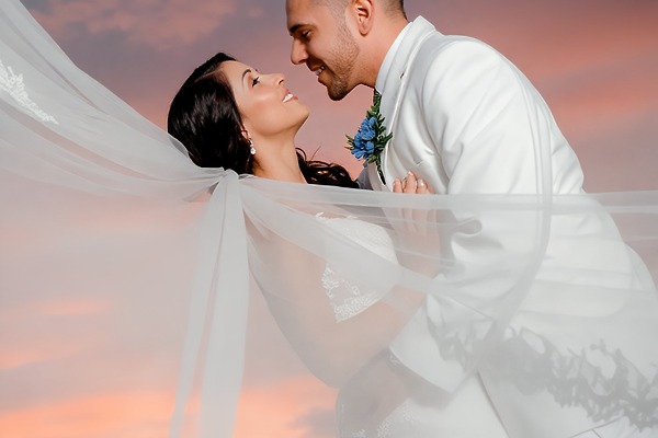 Bride and groom embrace at sunset during their destination wedding, veil flowing at Moon Palace Nizuc.