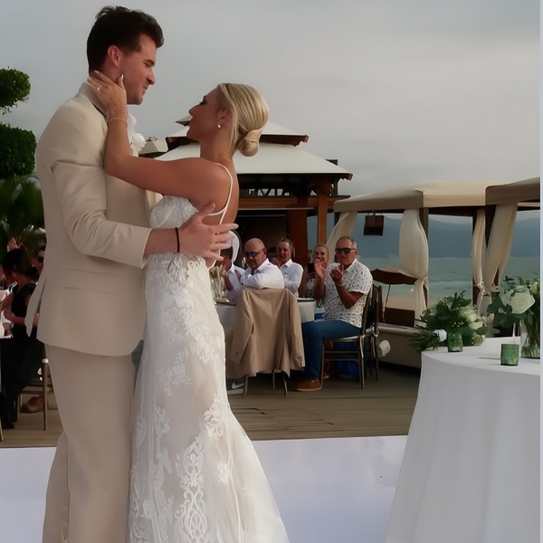 Leah and Christopher share their first dance outdoors at their destination wedding, surrounded by guests who watch and applaud.