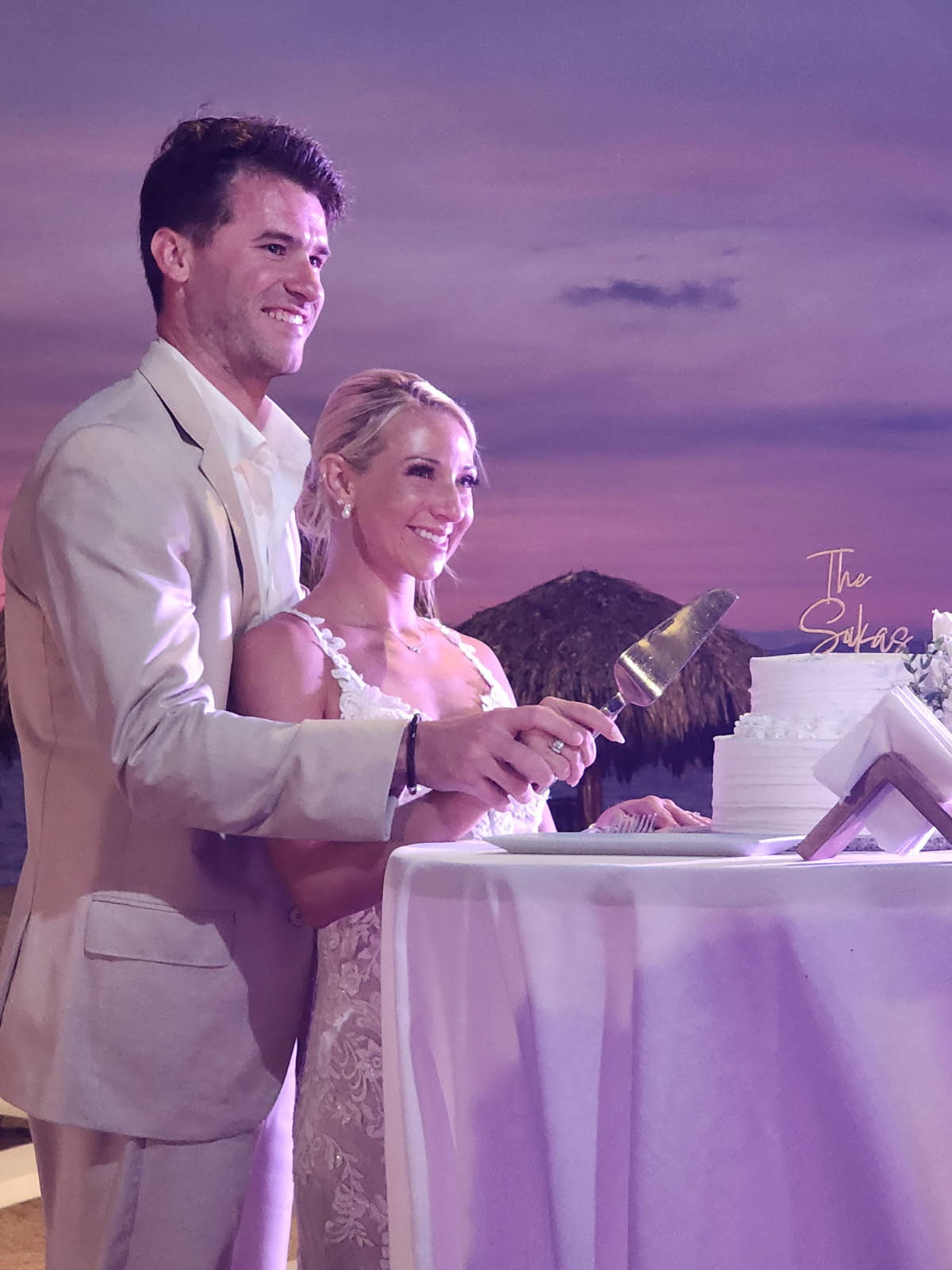 Leah and Christopher cut their wedding cake together during an outdoor evening celebration at their destination wedding.