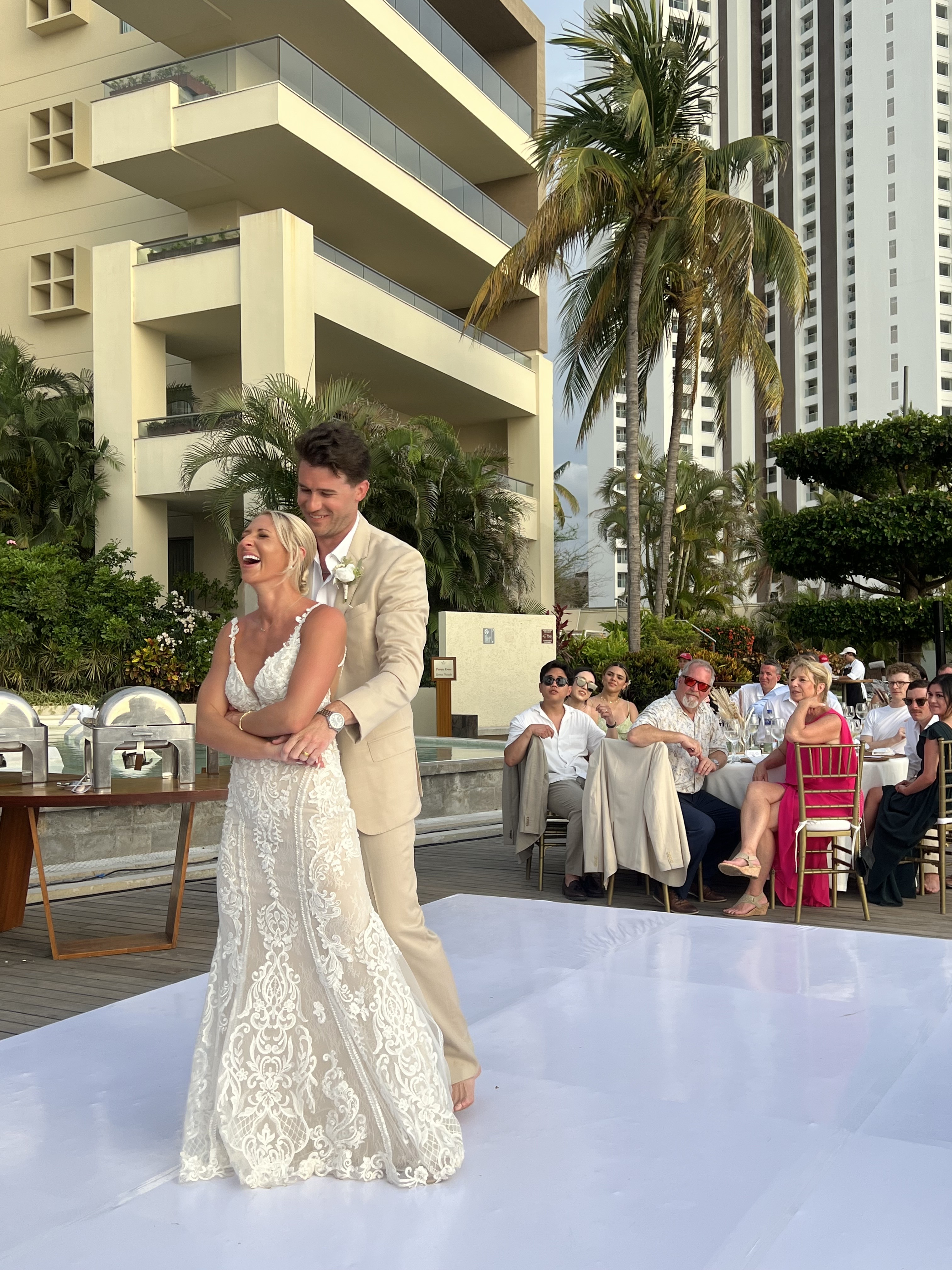 Leah and Christopher share a joyful dance outdoors at their destination wedding, smiling and embracing as they celebrate their special day.