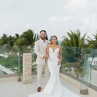 Trey and Kimberly stand on an outdoor terrace, surrounded by palm trees, celebrating their destination wedding.