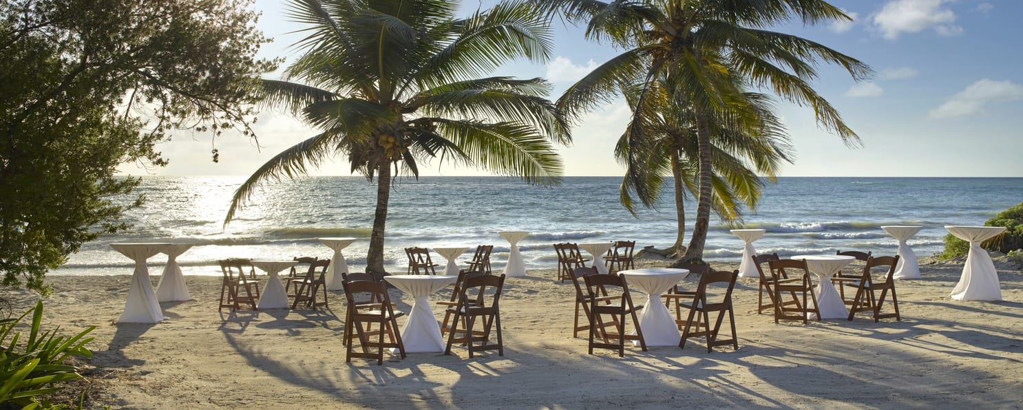Ideal for destination weddings, with chairs and cocktail tables arranged on a sandy beach.