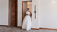 The bride, beaming as she enters in a stunning white Jordan and Kievan gown and holding a bouquet of flowers, brings joy to the destination wedding.