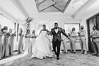 Jordan and Kievan walk down the aisle during their destination wedding, as their wedding party stands and applauds.