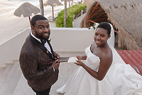 Saphire and Stephen, dressed in elegant formalwear, share a smile on the outdoor steps at their destination wedding, each holding a notebook.