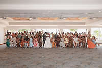 Jordan and Kievan stand at the center of a large destination wedding group posing indoors.