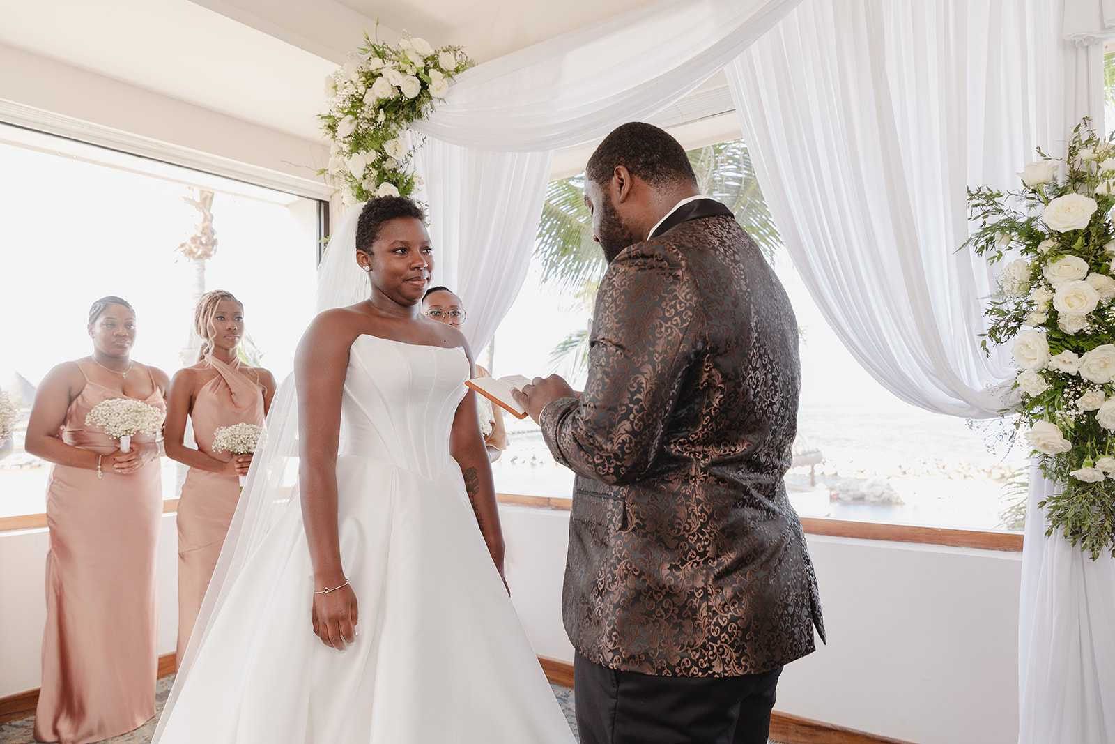 At their indoor wedding, Jordan and Kievan exchange vows with bridesmaids close by.