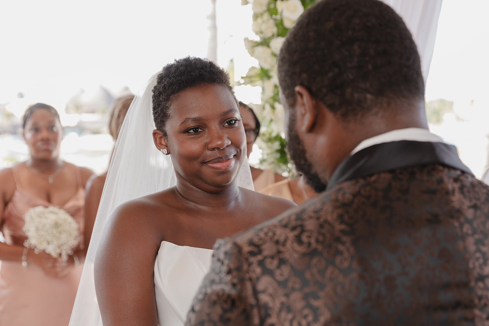Jordan and Kievan stand together at their destination wedding, bridesmaids lined up in the background.