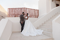 Saphire and Stephen stand together on white steps outside, gazing at each other fondly during their destination wedding.