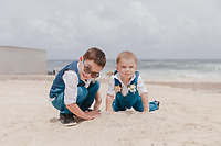 Teneal and Jonathan (Copy): At this destination wedding, two young boys in blue suits play in the sand beneath a cloudy sky.