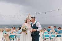 Teneal and Jonathan share a kiss during their destination wedding ceremony on the beach, with their guests seated behind them, witnessing the special moment.
