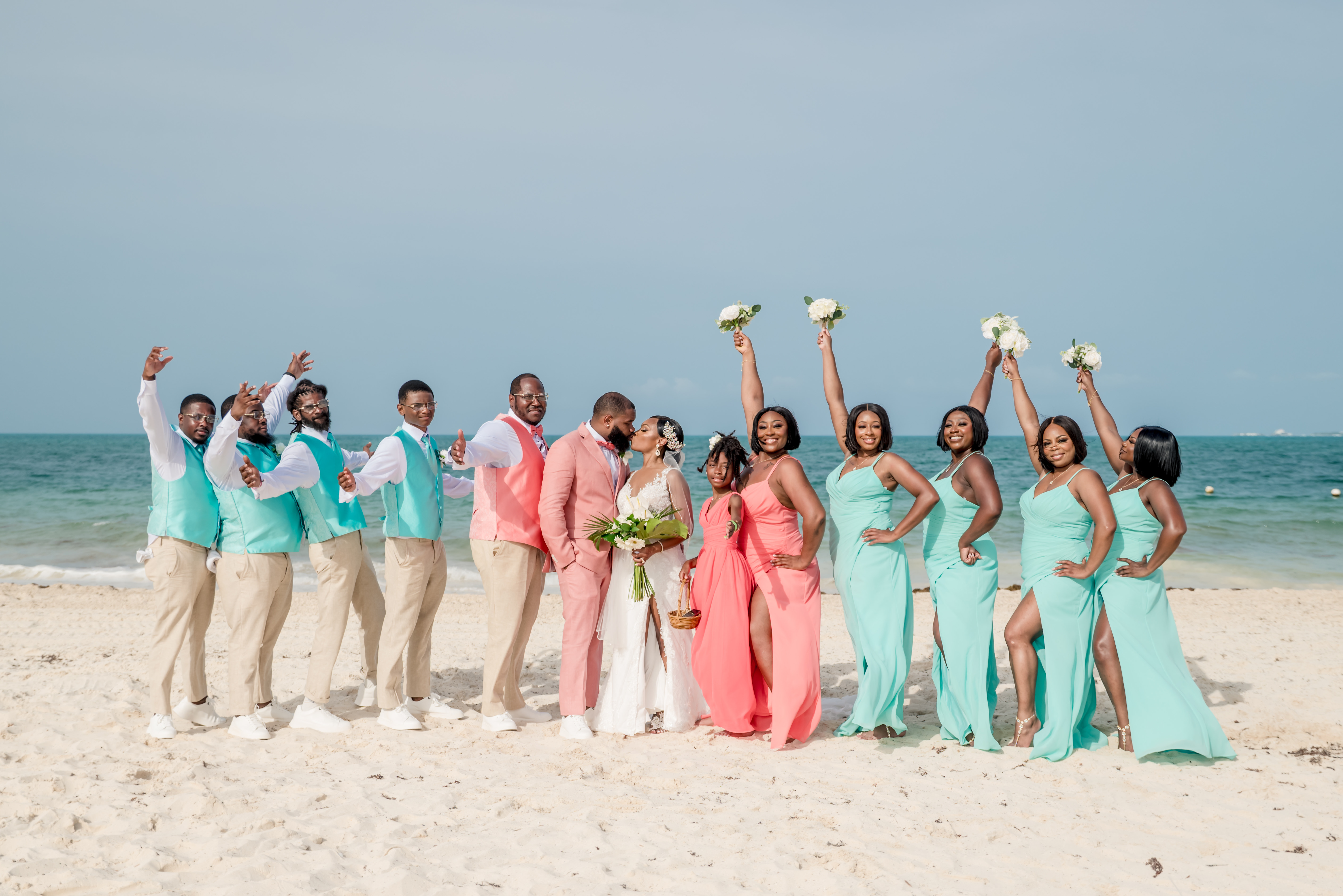 Sydney and Hayden’s destination wedding party celebrates on a sandy beach, with the sparkling ocean as their backdrop.