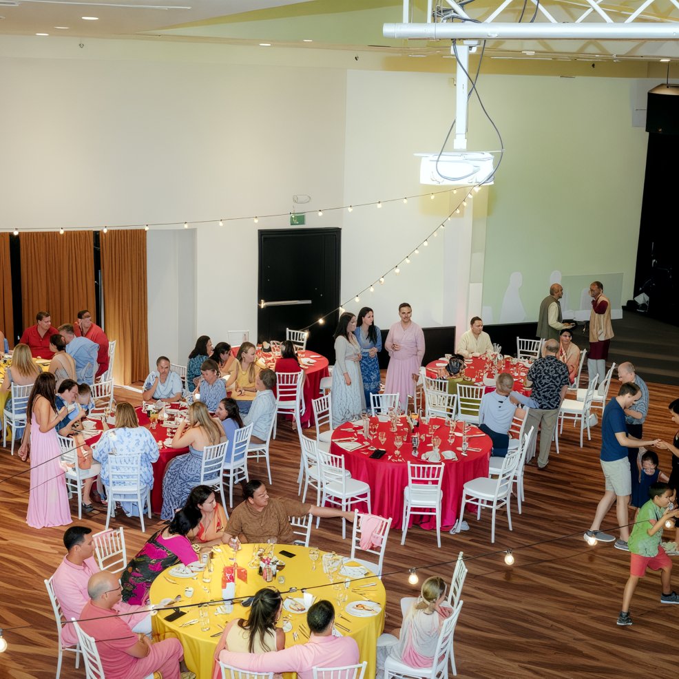 Guests seated at round tables with colorful tablecloths at an indoor destination wedding reception.