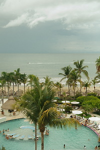 Stephanie and Mark’s destination wedding: Beachfront resort, pool, palm trees, and cloudy ocean views.