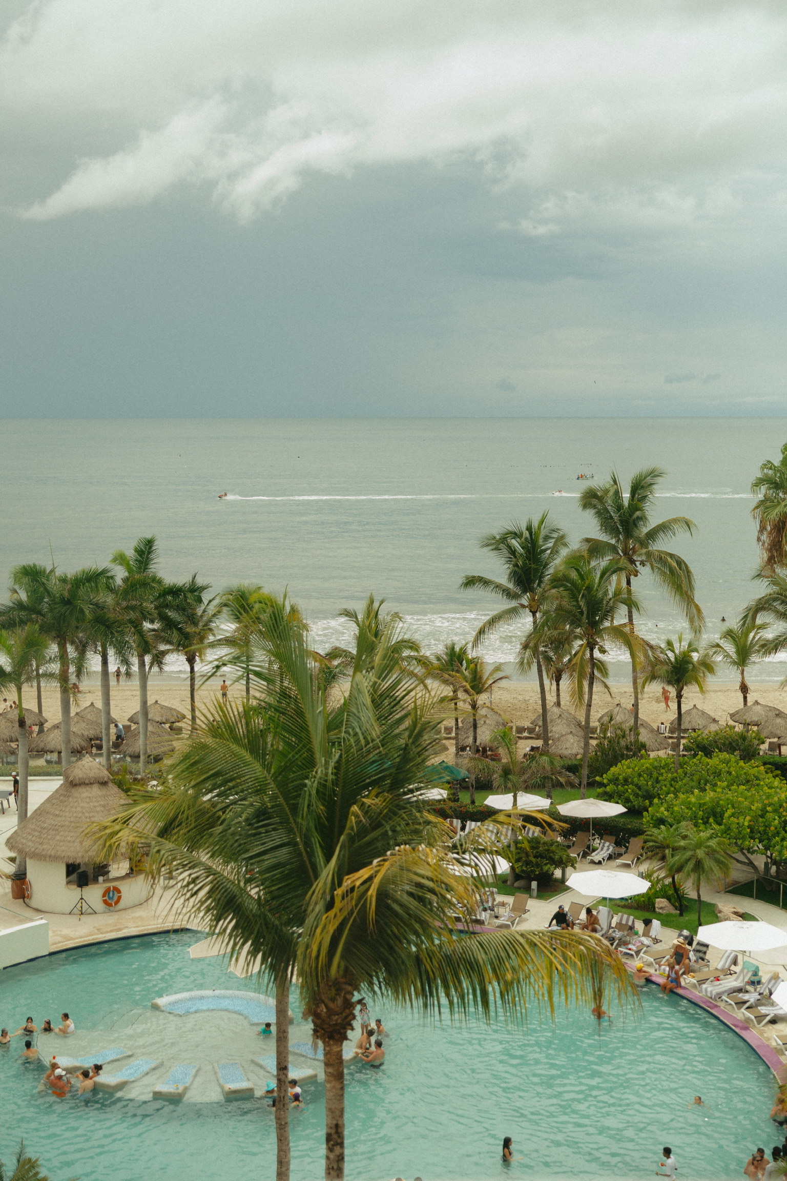 Stephanie and Mark’s destination wedding: Beachfront resort, pool, palm trees, and cloudy ocean views.