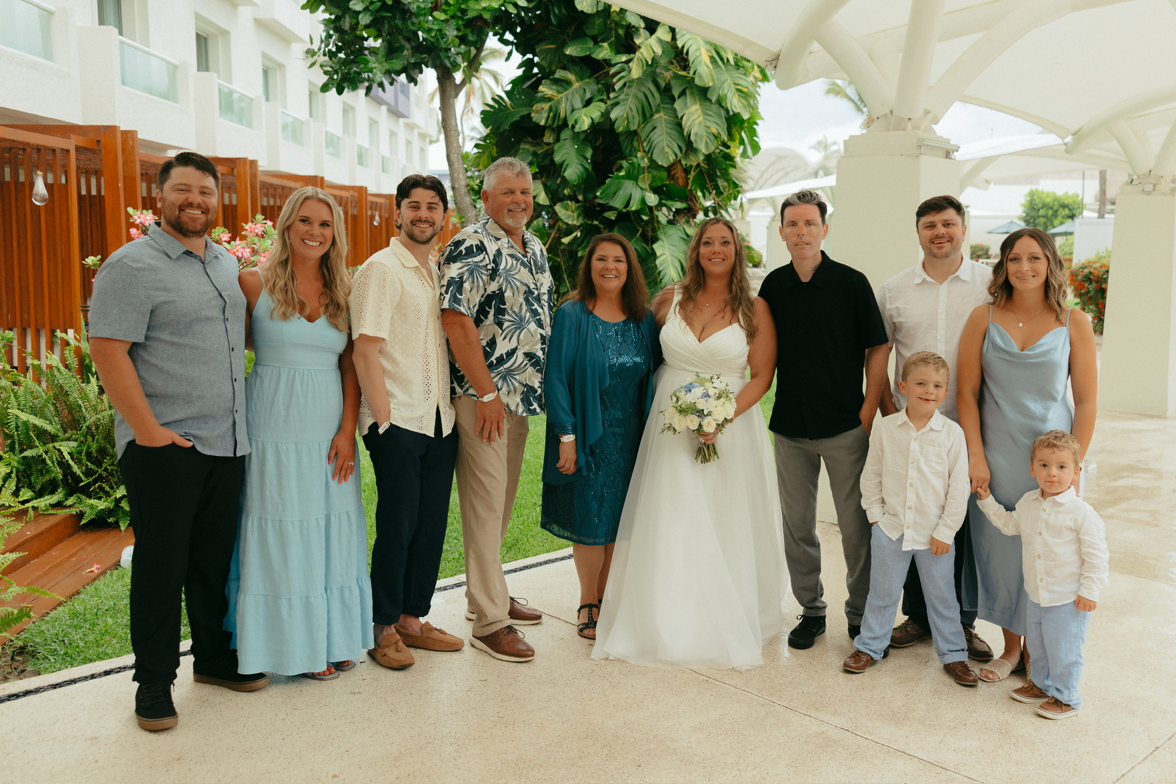 A wedding party poses outdoors at a destination wedding, bride in center holding her bouquet.