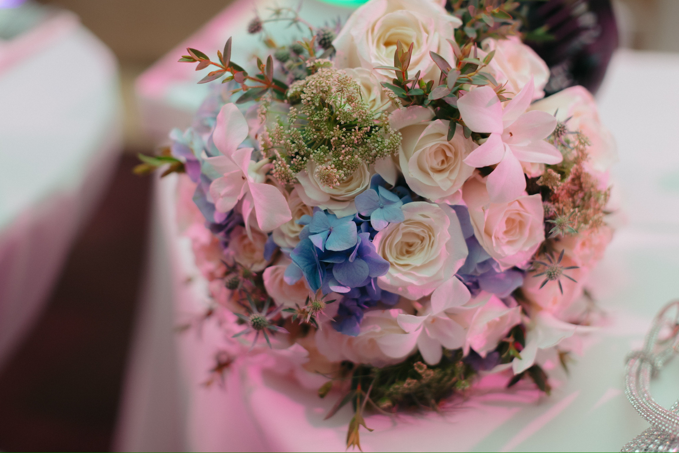 Bouquet of white roses, pink flowers, and blue hydrangeas on a table at a destination wedding.