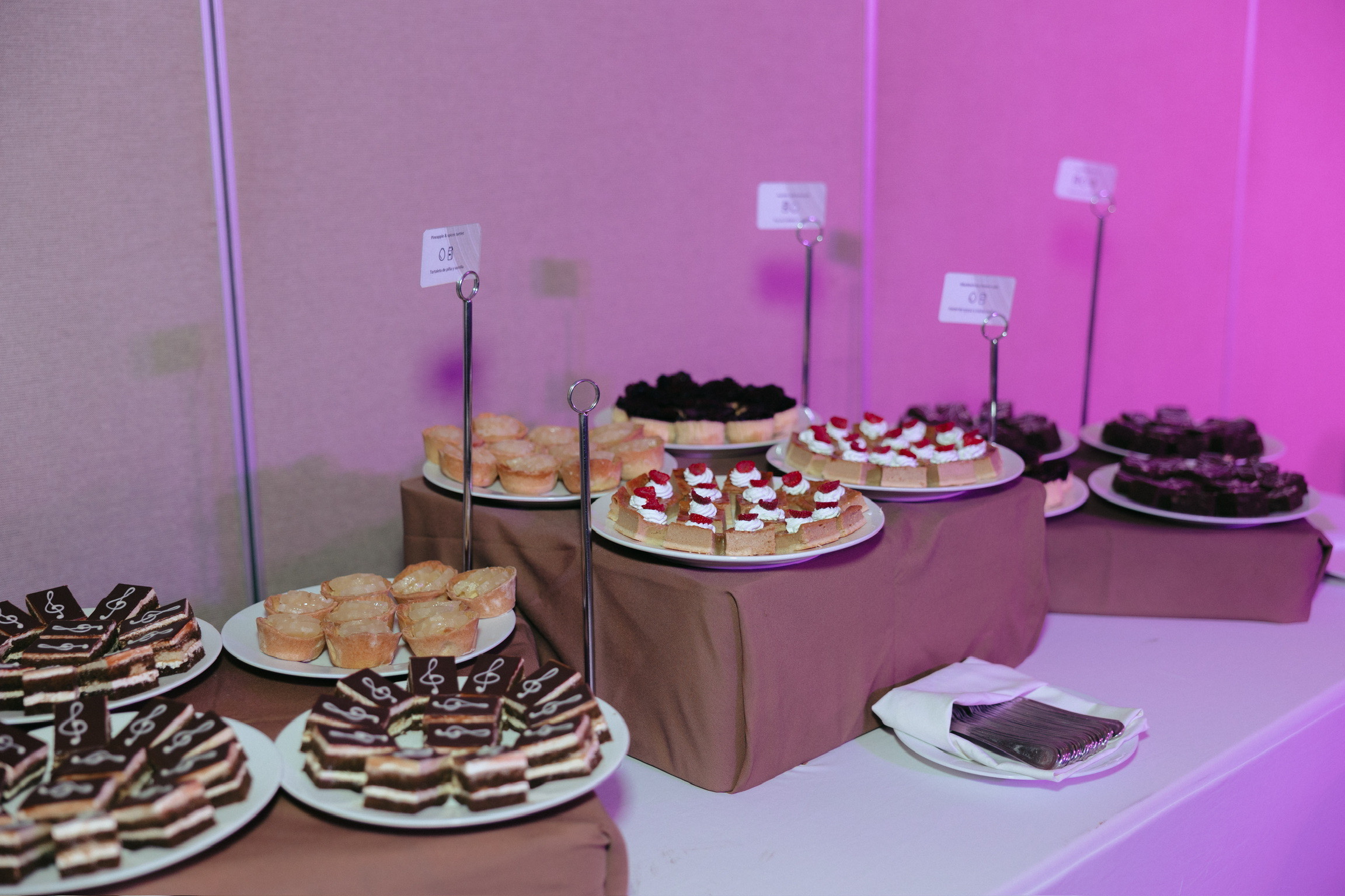 Desserts for Stephanie and Mark's destination wedding displayed on plates and stands on a brown table.