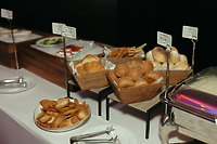 At the destination wedding, a buffet table displays bread rolls, toasted slices, and fresh salad.