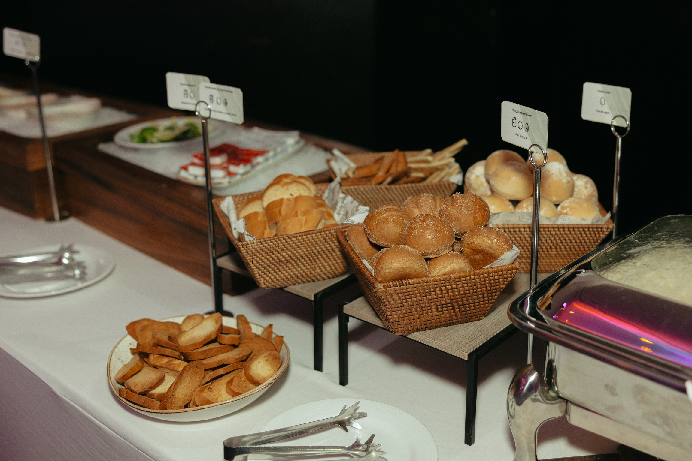 At the destination wedding, a buffet table displays bread rolls, toasted slices, and fresh salad.
