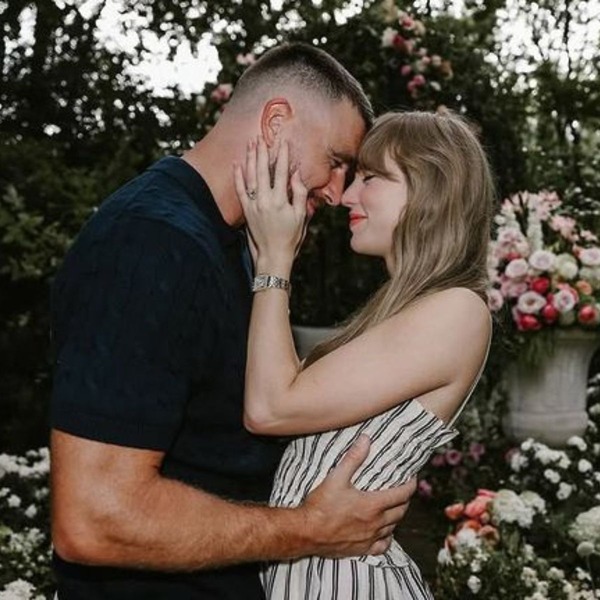 A couple embraces in a flower-filled garden, touching foreheads and smiling at their destination wedding.