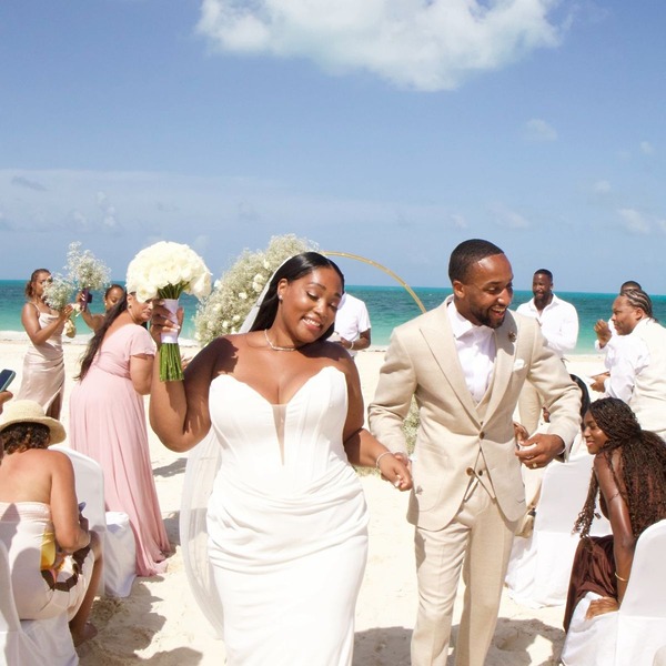 Jordan and Kievan stroll hand in hand down the sandy aisle, surrounded by loved ones celebrating their beautiful destination wedding.