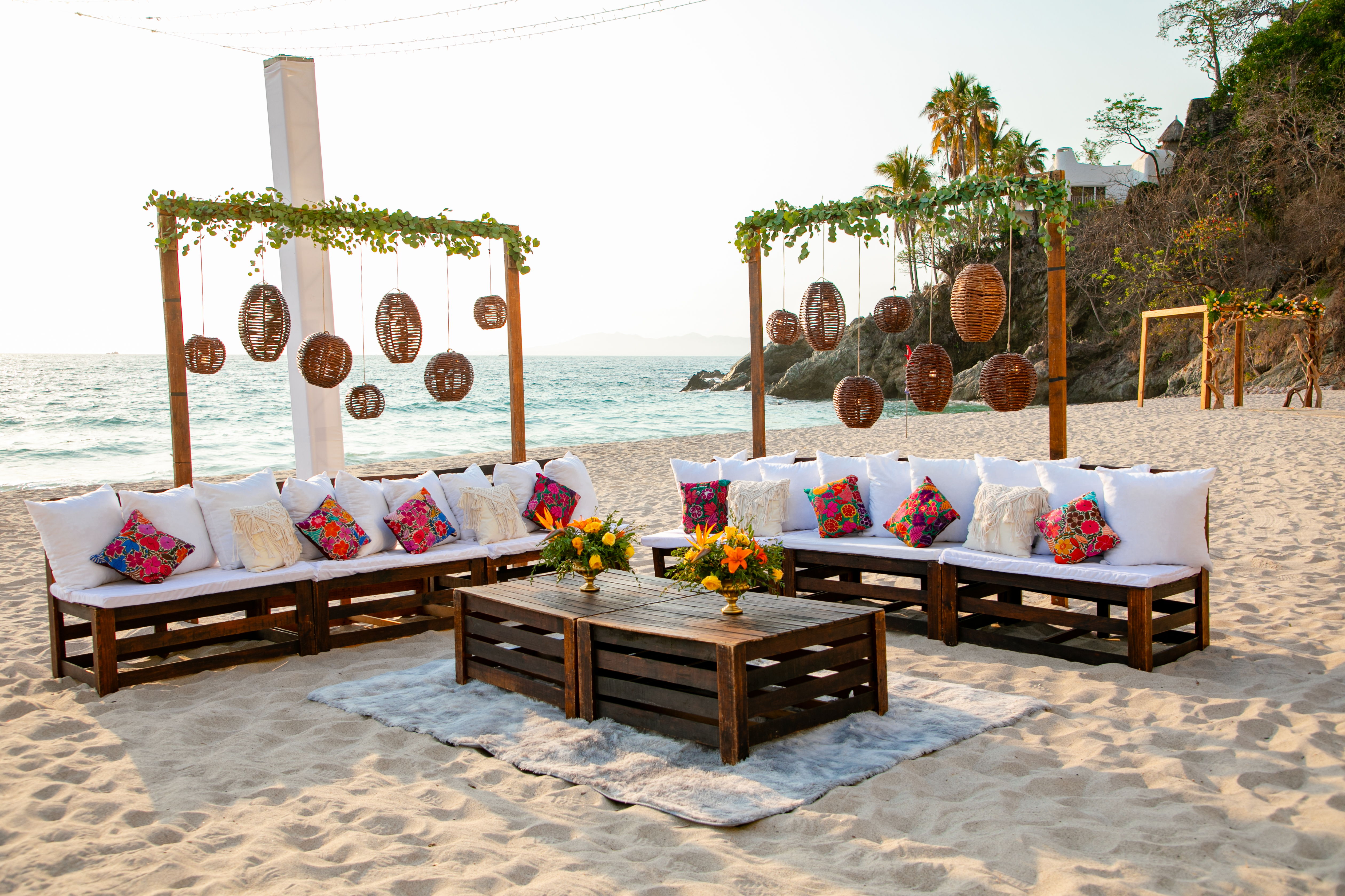Jordan and Kievan (Copy) destination wedding outdoor lounge: sandy beach setting with wooden seating, vibrant pillows, and lanterns—perfect for a relaxed seaside celebration.