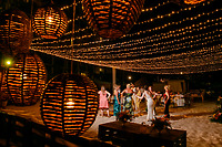 Guests dance barefoot on the sand beneath string lights and glowing Jordanian and Kievan lanterns, celebrating a magical destination wedding under the stars.