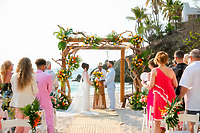 Jordan and Kievan exchange vows beneath a beautiful floral arch at their romantic beach destination wedding.