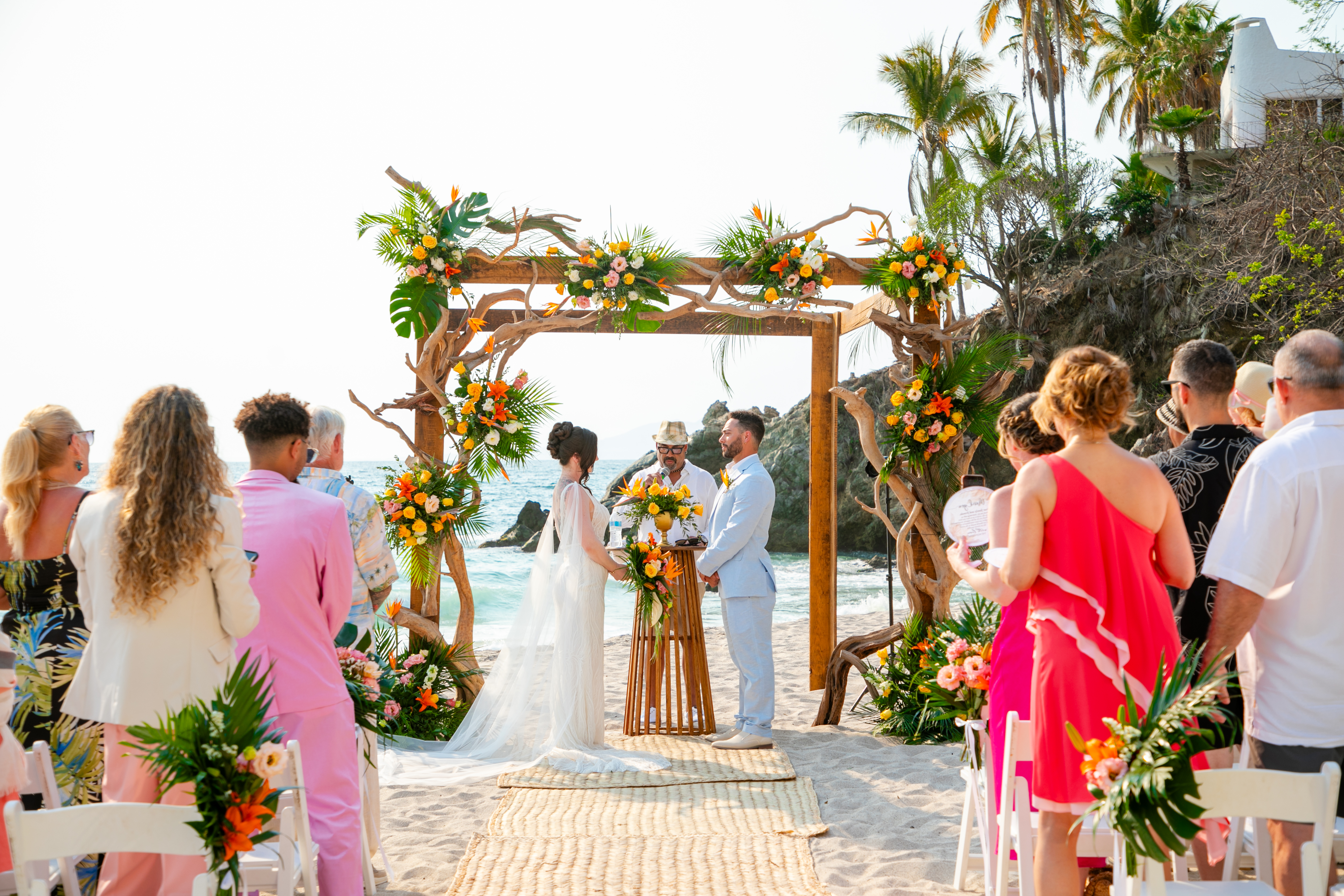 Jordan and Kievan exchange vows beneath a beautiful floral arch at their romantic beach destination wedding.