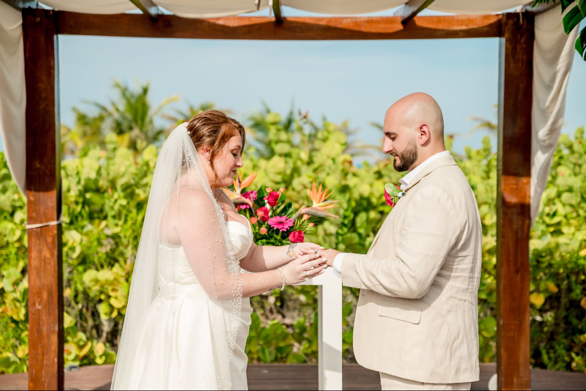 Mobolaji and Sylvia exchange rings beneath a canopy at their beautiful outdoor destination wedding.