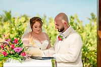 Mobolaji and Sylvia sign their wedding papers outdoors next to a flower arrangement at a destination wedding.