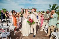 Mobolaji and Sylvia sip drinks together as they walk down the aisle at their outdoor destination wedding.