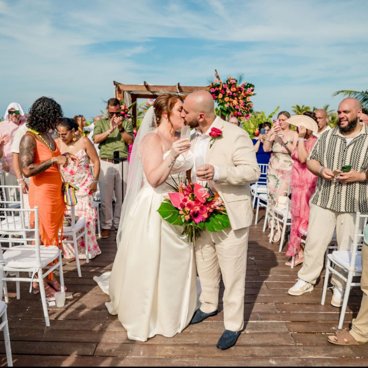 Mobolaji and Sylvia share a kiss during their destination wedding, cheered on by joyful wedding guests.