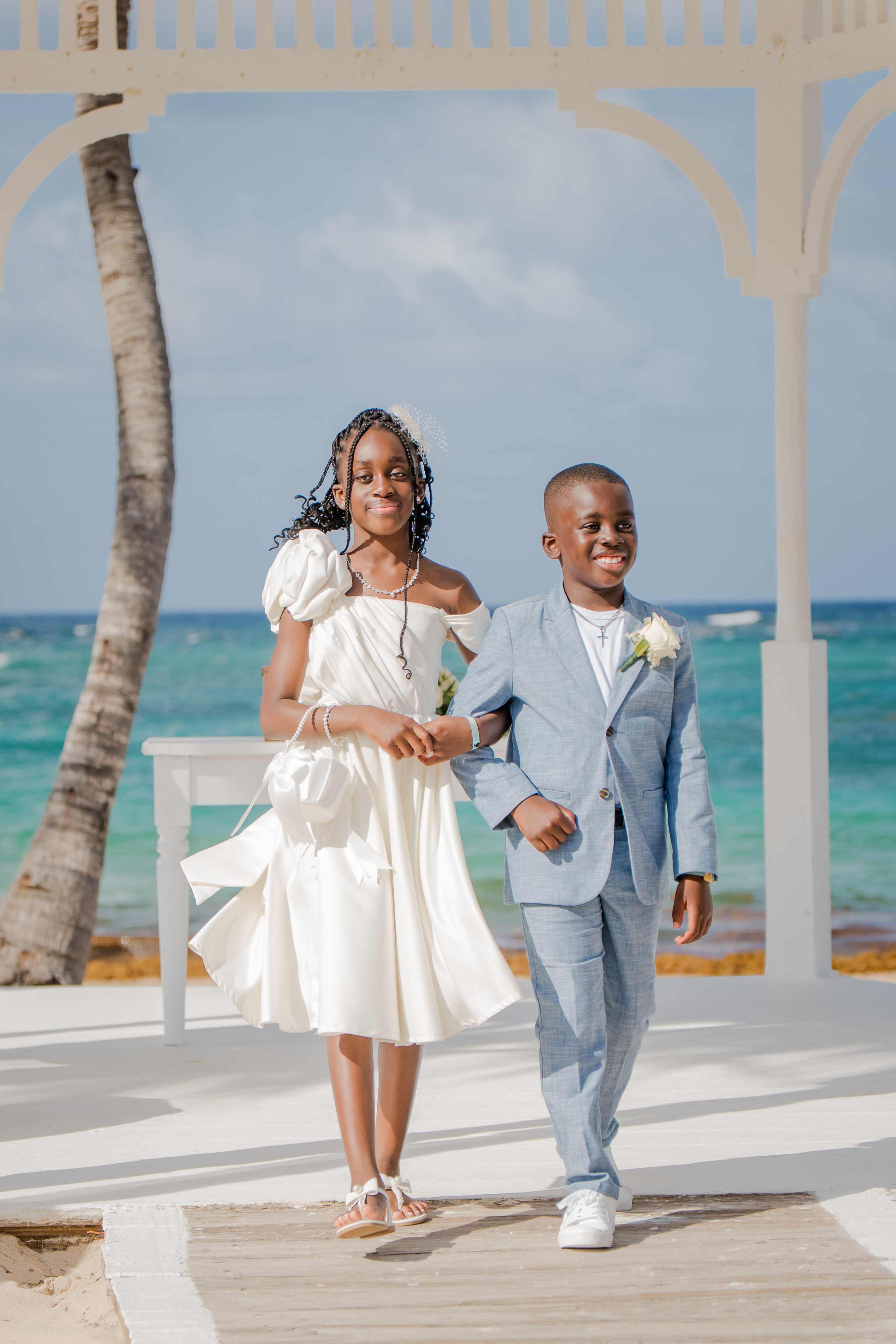 Mallory and Kharey (Copy) walk together at an outdoor beachside destination wedding venue.