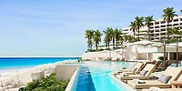 Infinity pool with lounge chairs, palm trees, and a modern hotel—perfect for a destination wedding.