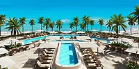 Luxury resort pool area set for a destination wedding, with lounge chairs, palm trees, and ocean views.