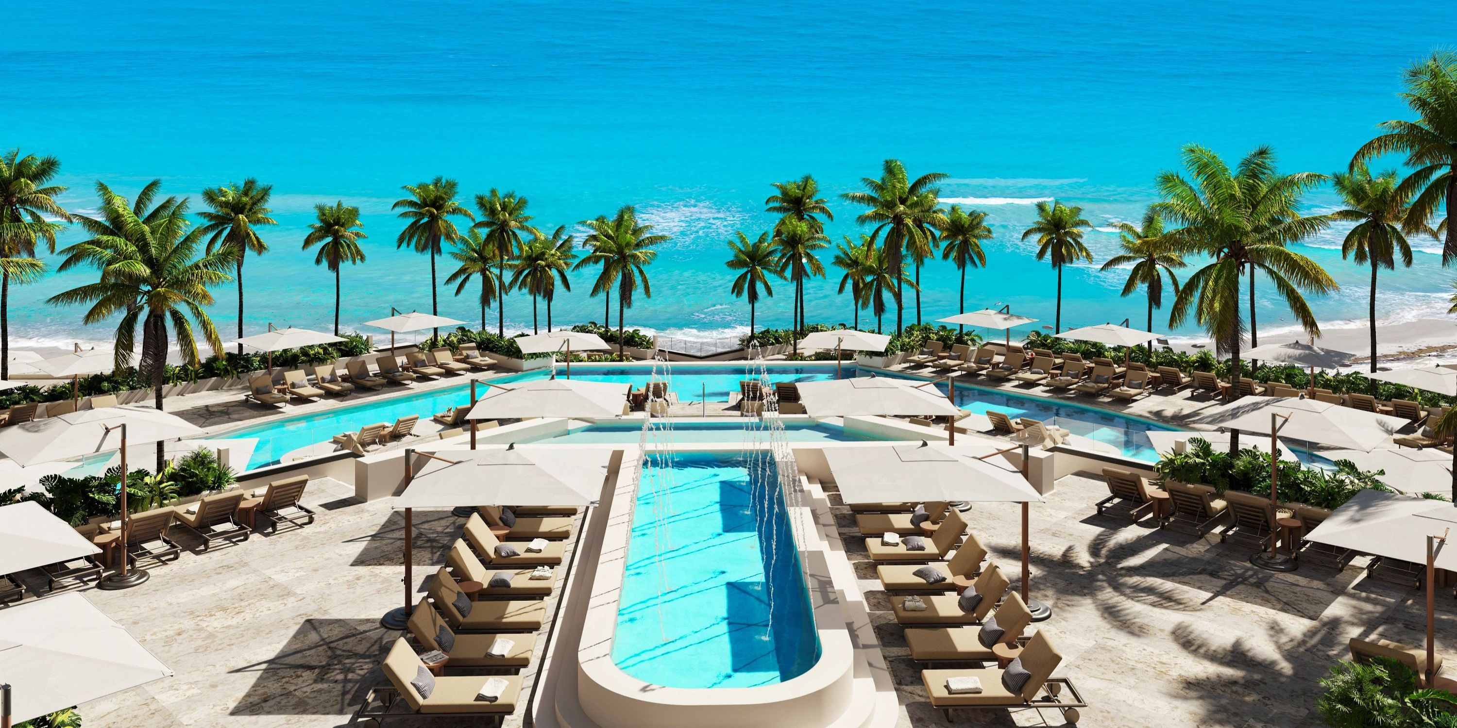 Luxury resort pool area set for a destination wedding, with lounge chairs, palm trees, and ocean views.