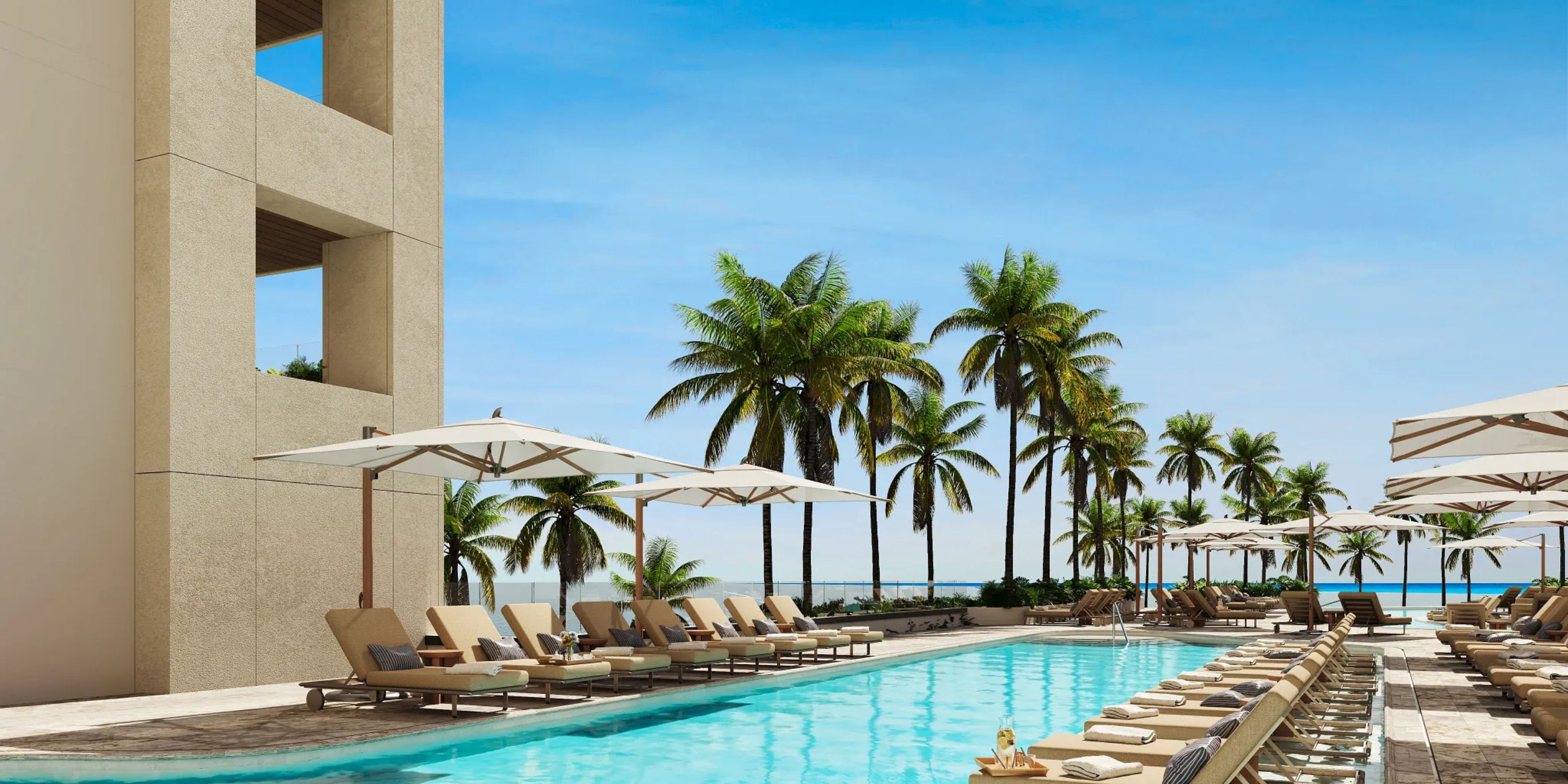 Outdoor pool with lounge chairs overlooks the ocean, ideal for a romantic destination wedding at Secrets Mirabel Cancun.