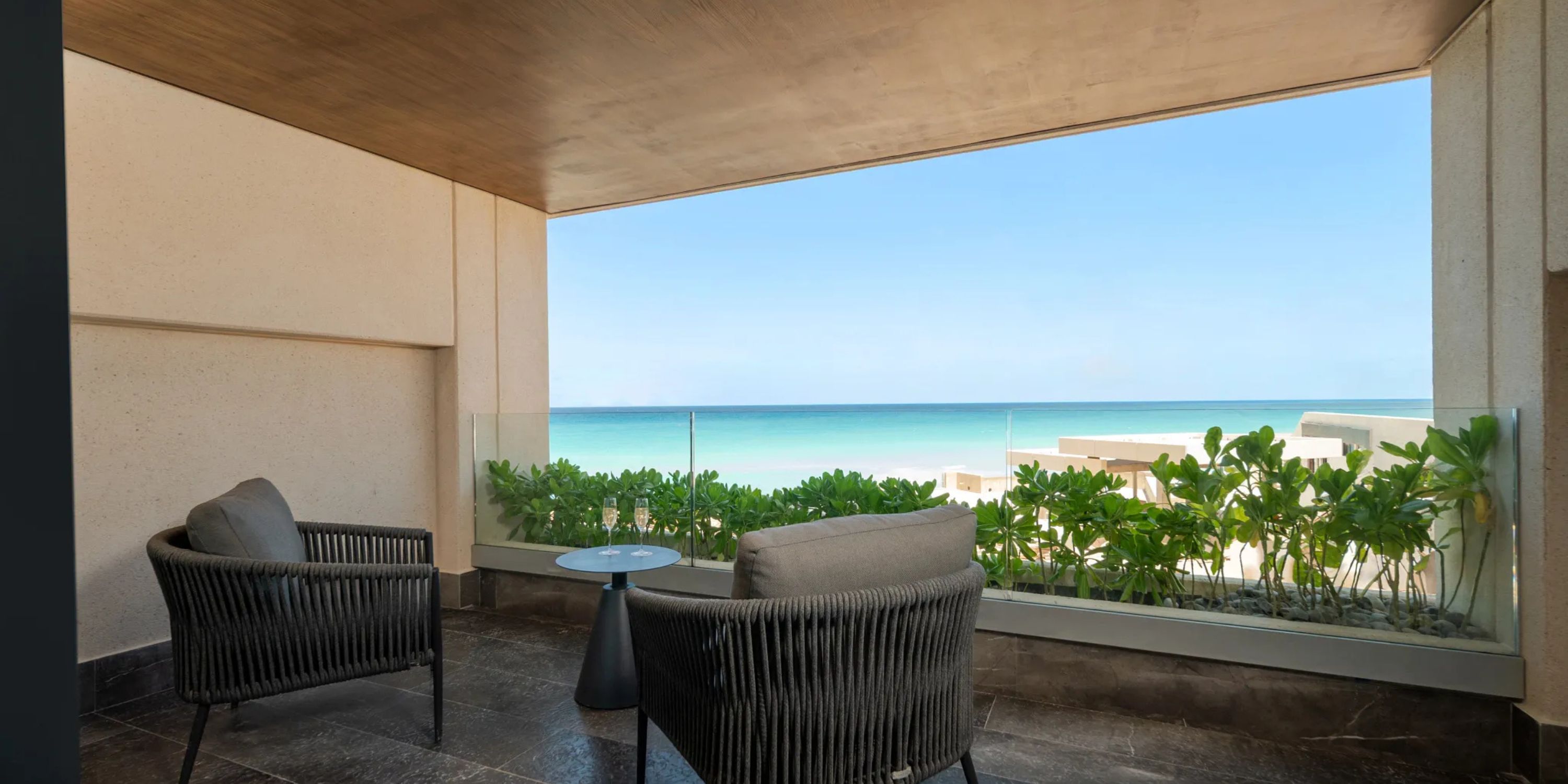 Two chairs and a small table on an ocean-view balcony at a popular Cancun destination wedding resort.