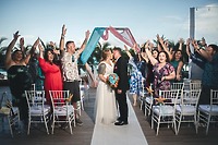 Mobolaji and Sylvia share a kiss at their destination wedding, surrounded by cheering guests.