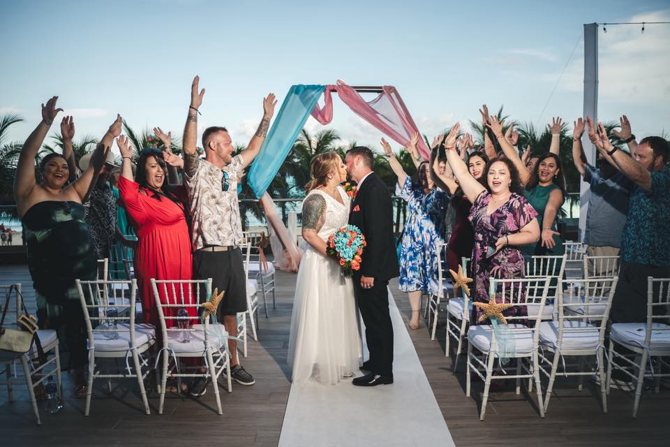 Mobolaji and Sylvia share a kiss at their destination wedding, surrounded by cheering guests.