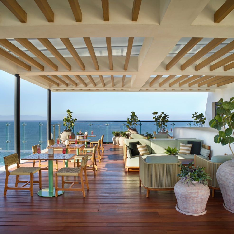 Stunning outdoor terrace with wood floors, modern seating, glass rails, and perfect for a destination wedding.