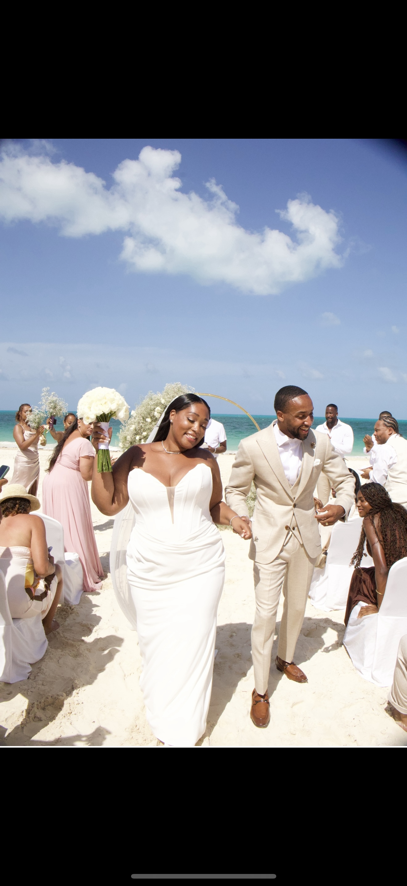 Jordan and Kievan walk down the aisle on a beautiful beach, surrounded by their wedding guests at their destination wedding.