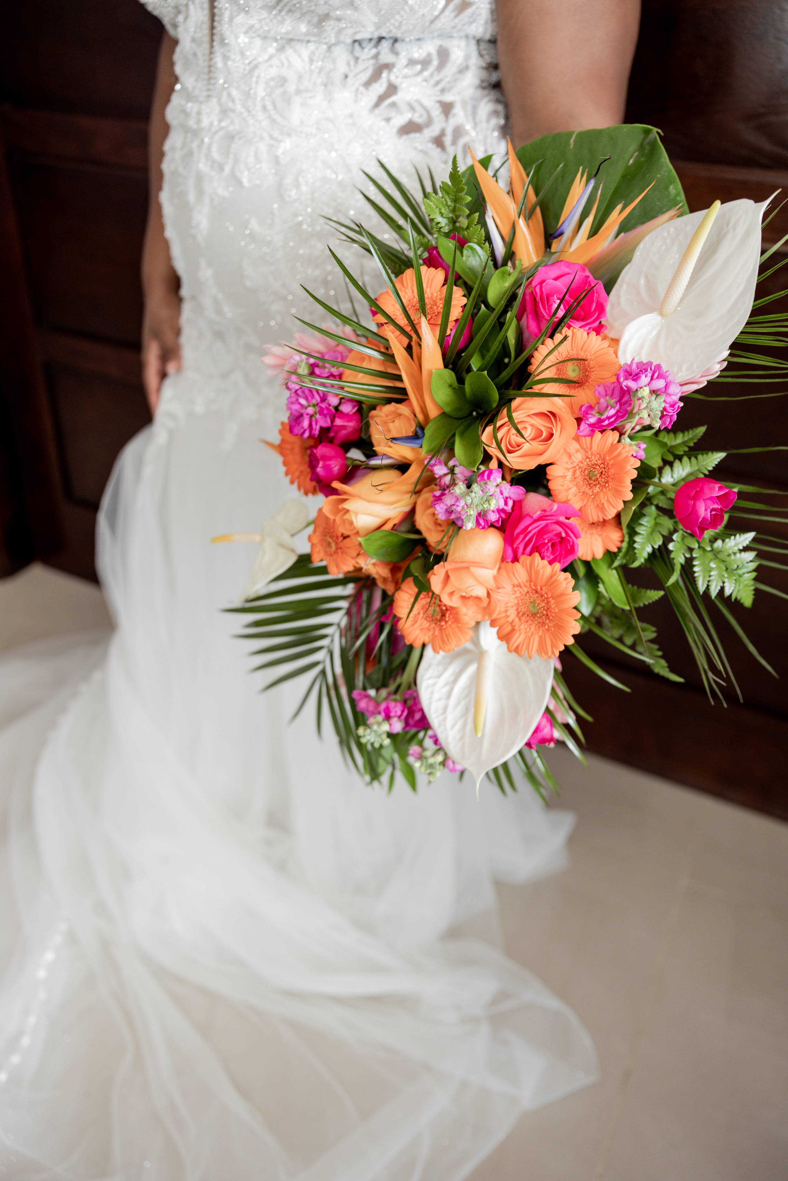 Bride at destination wedding holds a vibrant April and Javiert bouquet of orange, pink, and white flowers.